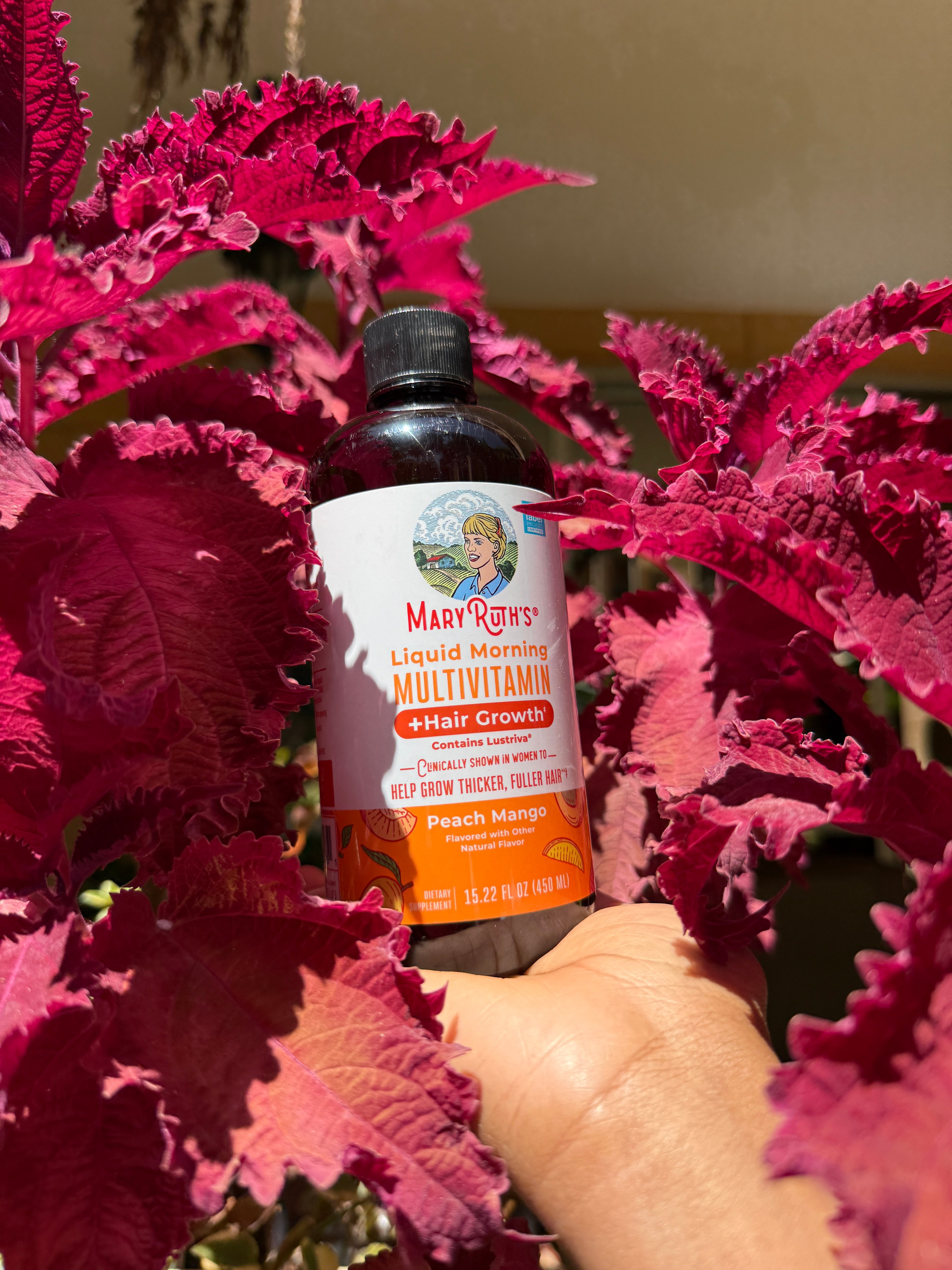 Bottle of Mary Ruth's Multivitamin for Kids amidst pink leafy plants